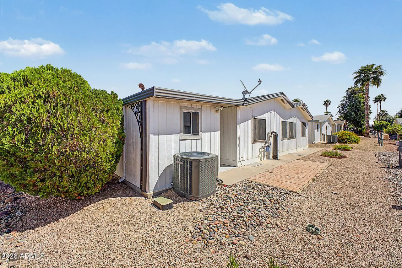 Front elevation with driveway and desert landscaping under blue Arizona sky